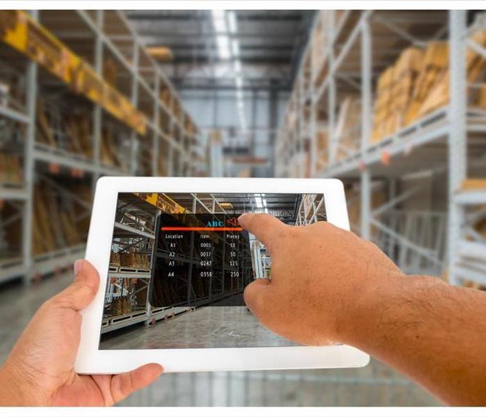 Hand hold and touching digital tablet with smart inventory application on screen in the warehouse.
